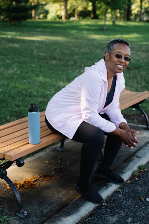 Free Woman in White Jacket and Black Legging Sitting on a Bench Stock Photo