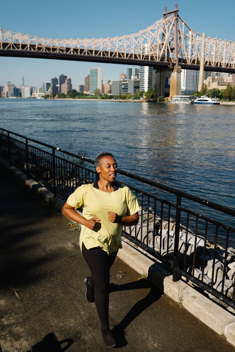 Woman Running Near A River And Bridge