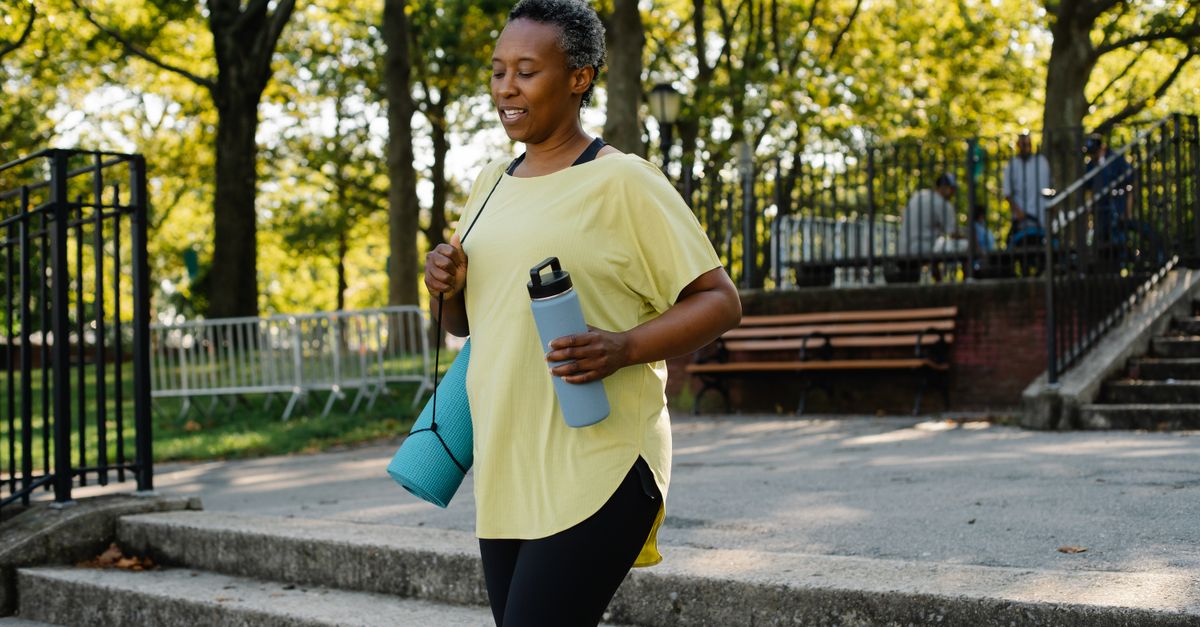 Person walking in a sunlit park, looking relaxed and happy, not sweating or wearing tight activewear