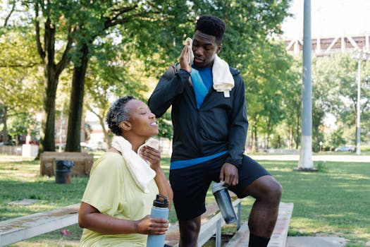 A mother and son enjoying a break on a sunny day in a park, cooling down with towels.