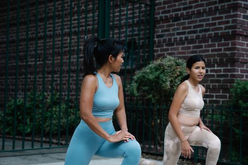 Free Mother and daughter stretching on the sidewalk in sports clothing, focused on fitness. Stock Photo