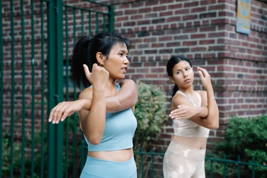 Two women in activewear stretching outdoors, promoting a healthy lifestyle.