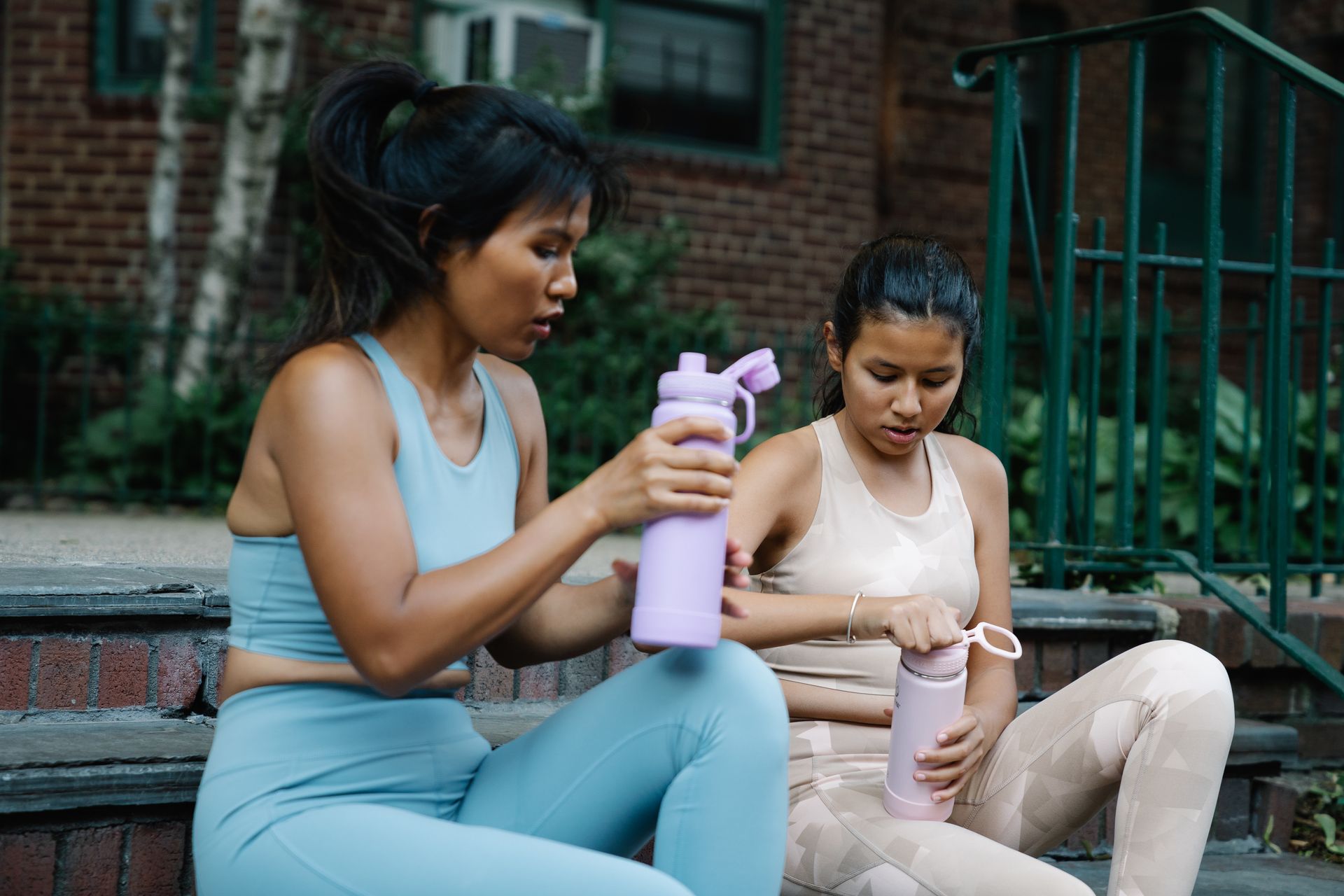 Women in Active Wear Sitting on a Concrete Stairs while Holding a Tumbler