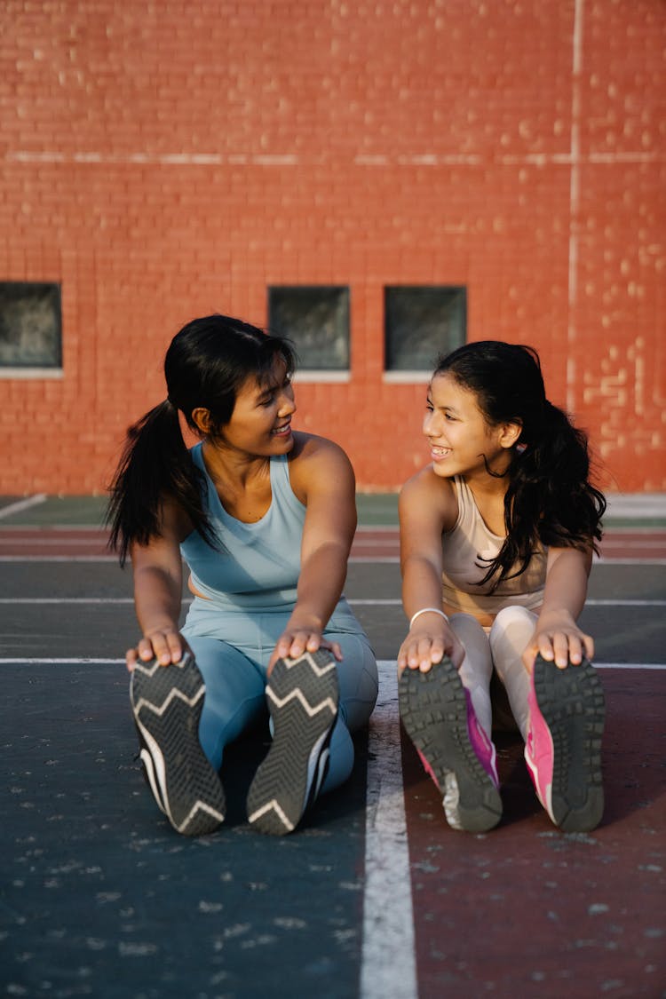 Mother And Daughter Doing Exercise On The Ground