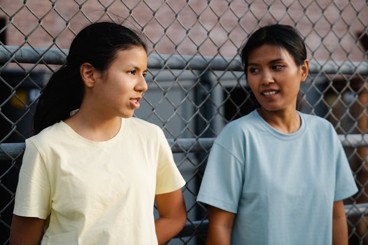 Women Standing Near The Fence Talking