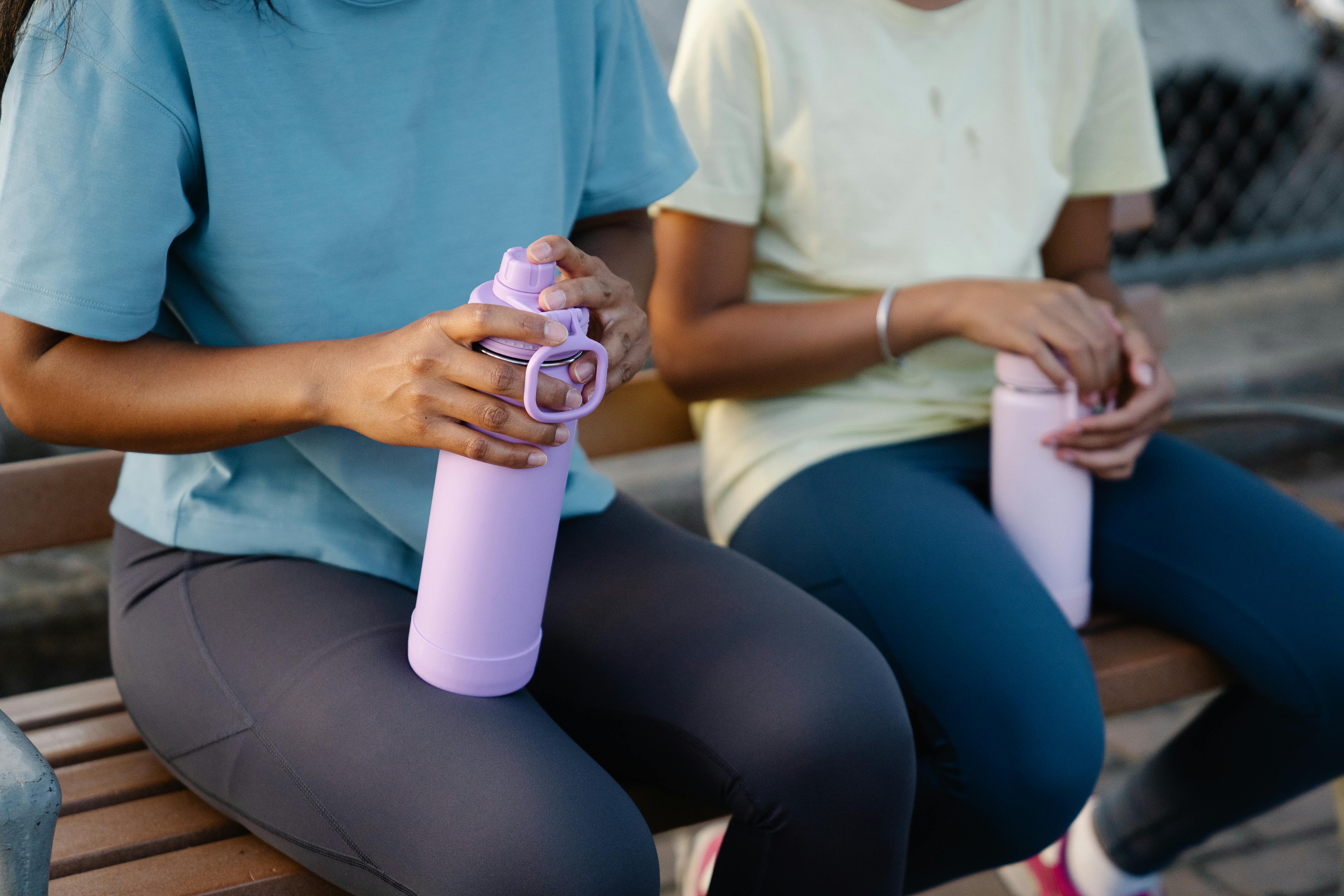 Free People Sitting on a Bench while Holding Tumblers Stock Photo