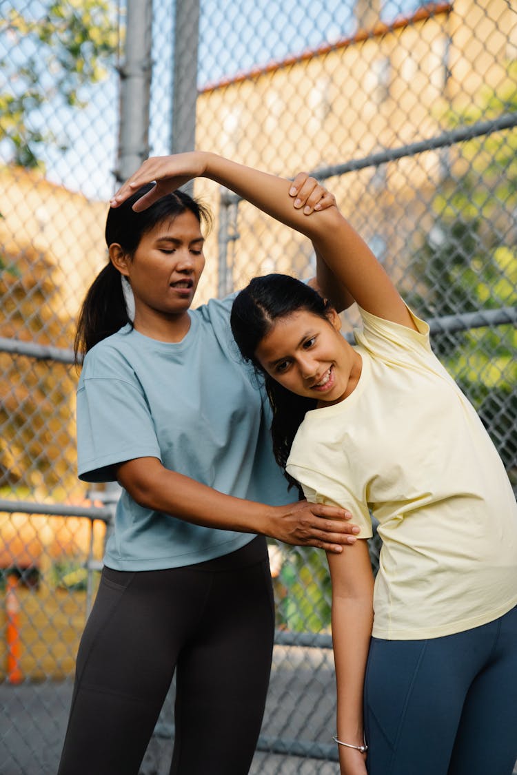 A Woman Guiding The Girl Stretch Her Arms