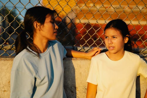 Girls Standing Against Mesh Fence