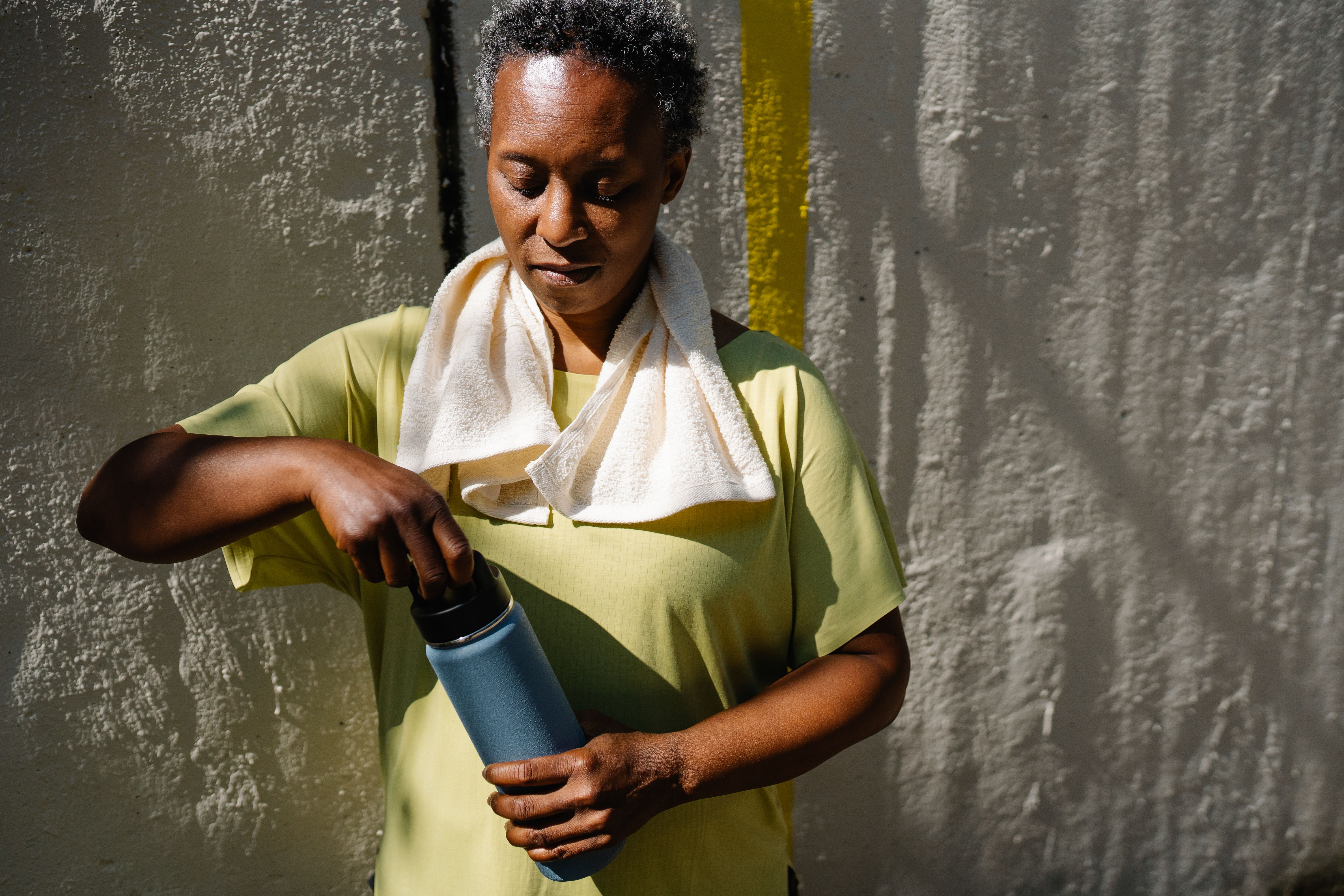 African American woman with a towel and water bottle in a sunny outdoor setting.