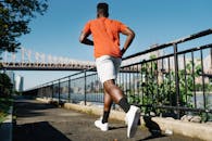 在河边的小路上慢跑的人，身后是城市中的桥梁和天际线