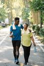 Mother and Son Holding Tumblers while Walking on the Street Together