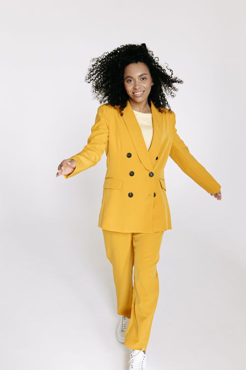 Free Vibrant portrait of a woman in a stylish yellow suit, exuding confidence and joy. Stock Photo