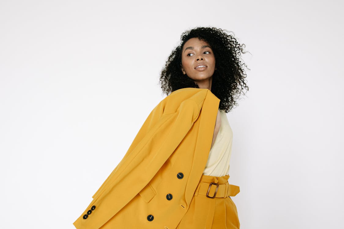 Woman in Yellow Outfit with Her Coat Over Her Shoulder · Free Stock Photo