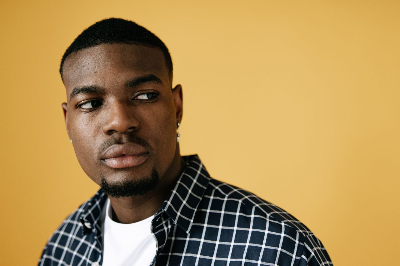 studio portrait of an adult male with a thoughtful expression on a yel