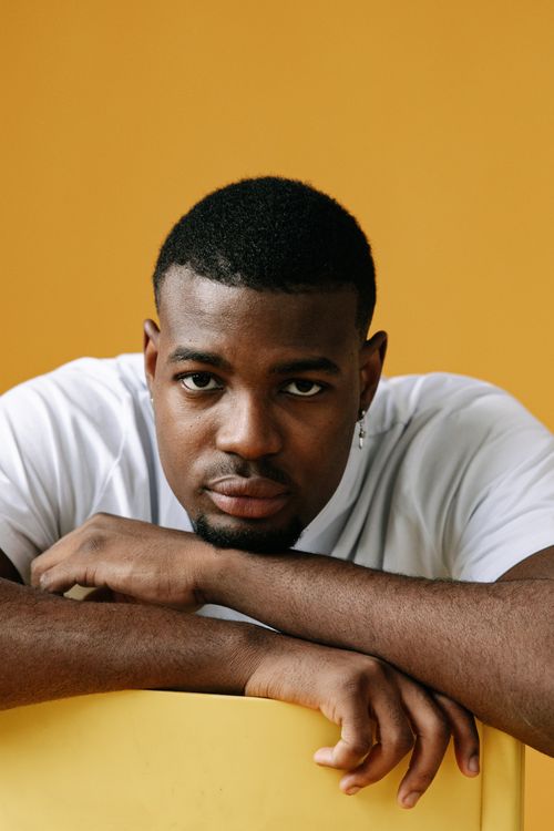 Free A thoughtful portrait of a man in a white t-shirt indoors with a yellow background. Stock Photo