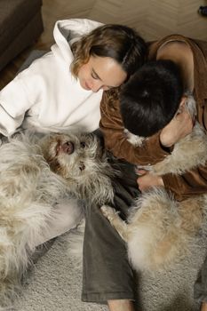 A couple cuddles with their fluffy dogs on a cozy indoor afternoon.
