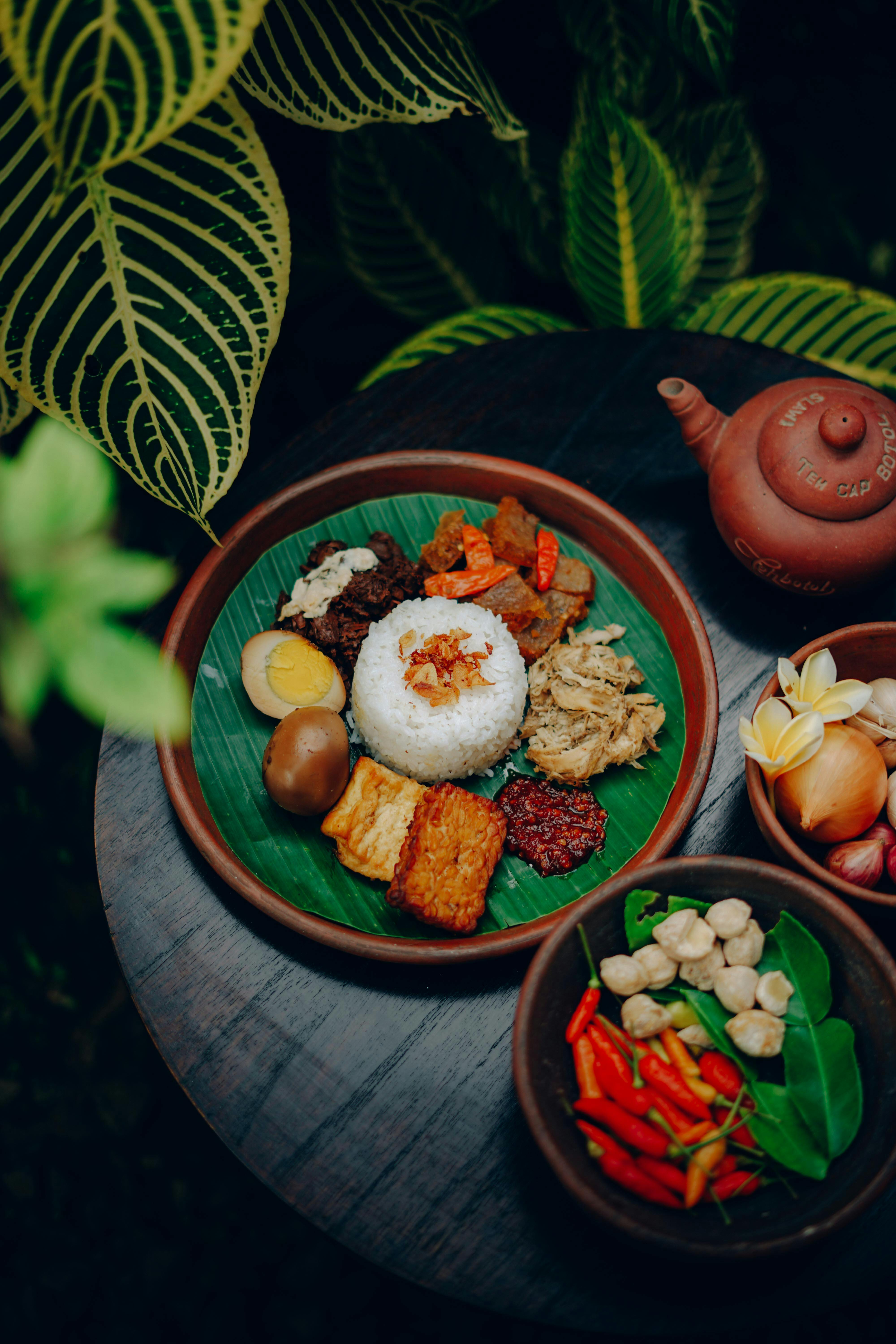 An appetizing traditional Indonesian dish with rice, vegetables, and side bowls on a wooden table.