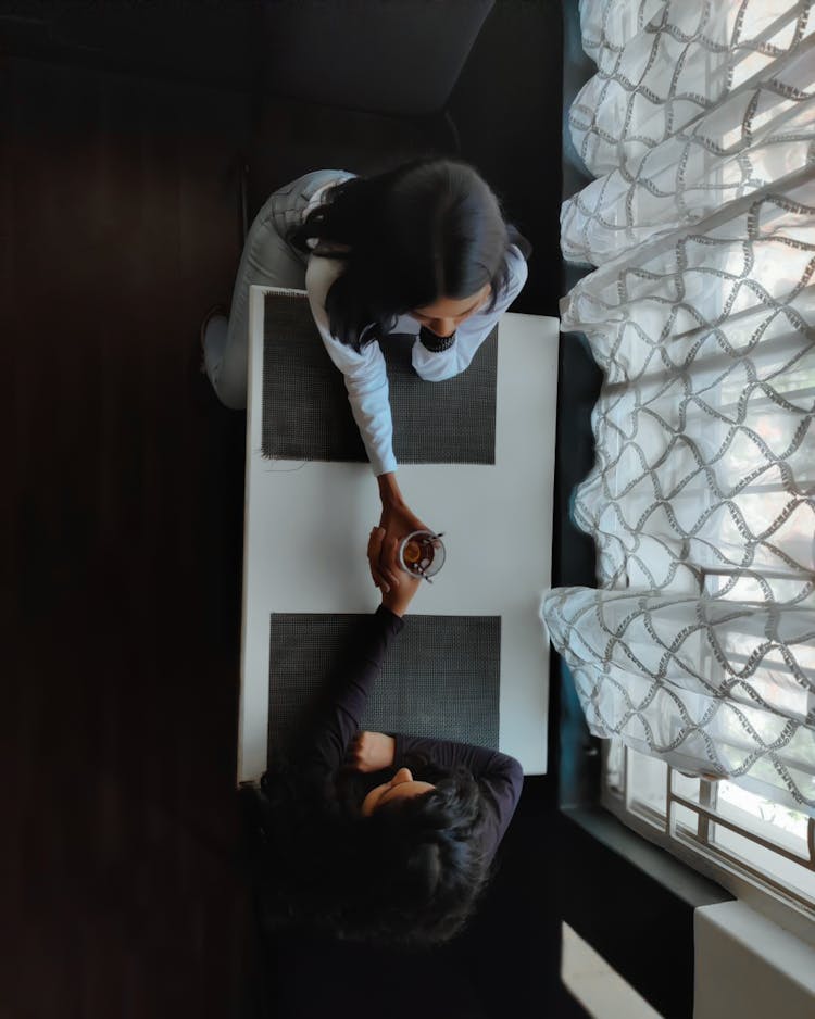 Top View Of Women Sitting Opposite Each Other At The Table 