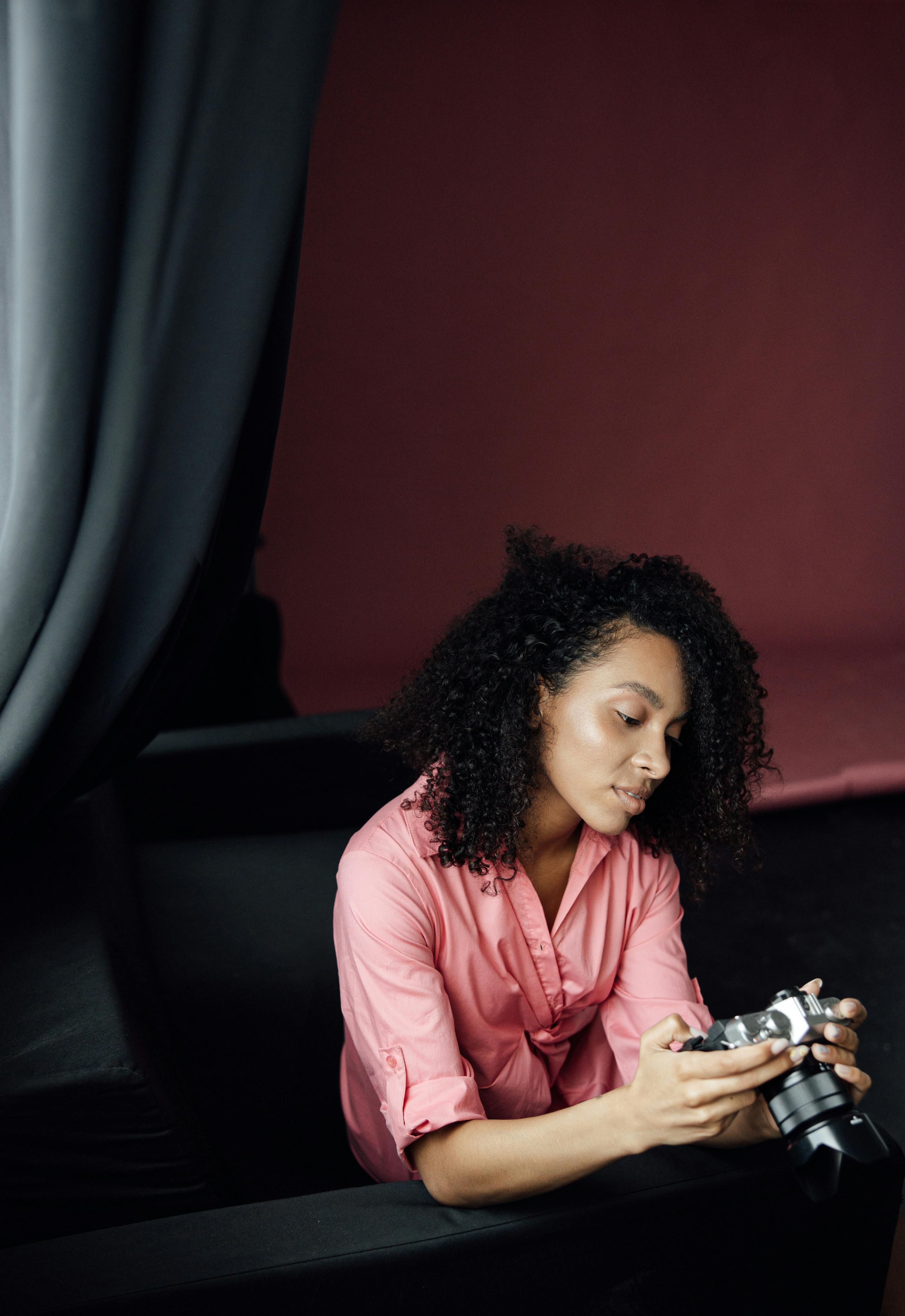 Focused woman photographer examining her camera in a studio setting.