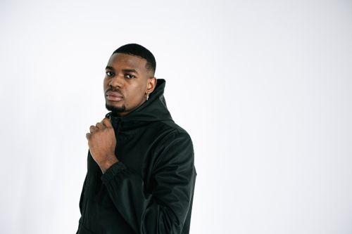 Free A close-up portrait of a serious man wearing a black hoodie against a white background. Stock Photo