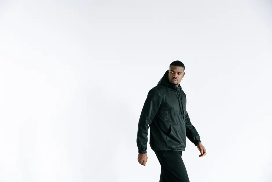 Modèle masculin en blouson streetwear noir porté avec ensemble coordonné sombre