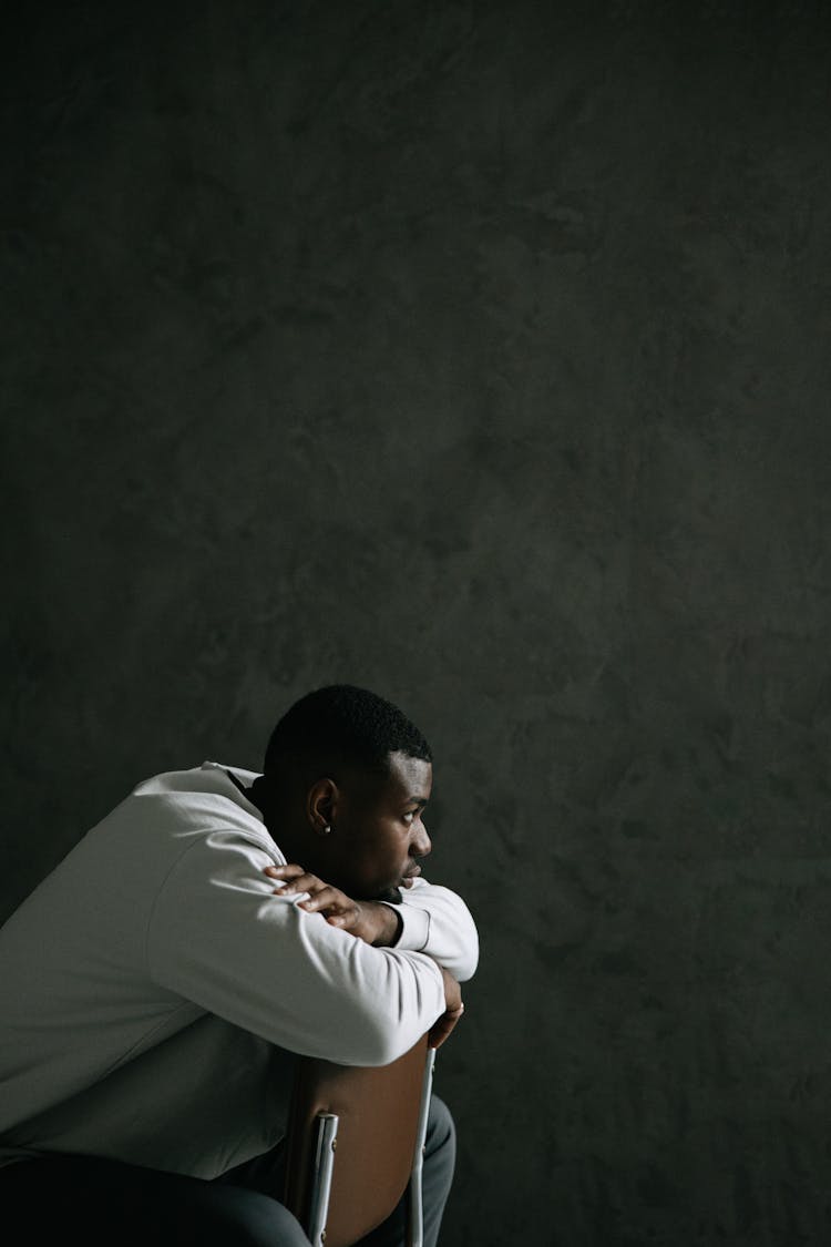 A Man In White Sweater Sitting On The Chair