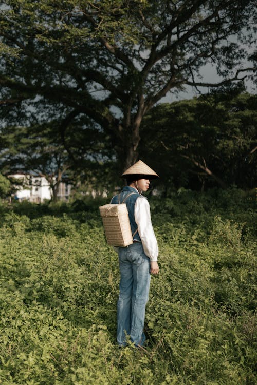 Man in Denim Vest Standing on Grass Field 