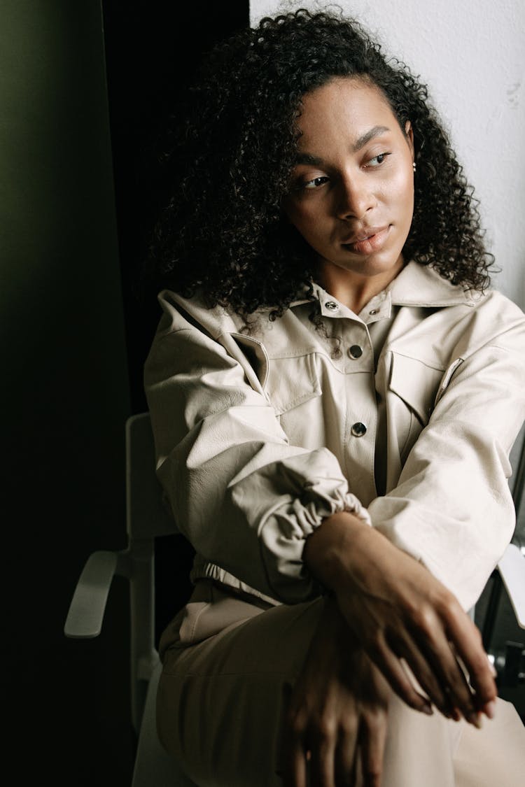 A Woman In Beige Jacket Sitting On The Chair