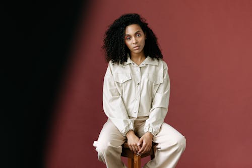 A Woman in White Jacket Sitting on a Wooden Stool