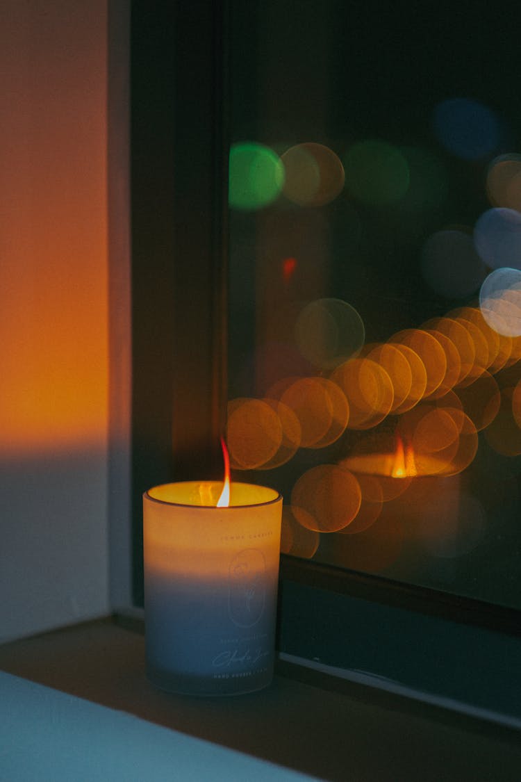 A Burning Candle On A Window Sill