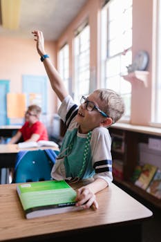 A young boy eagerly participates in an elementary school classroom setting.
