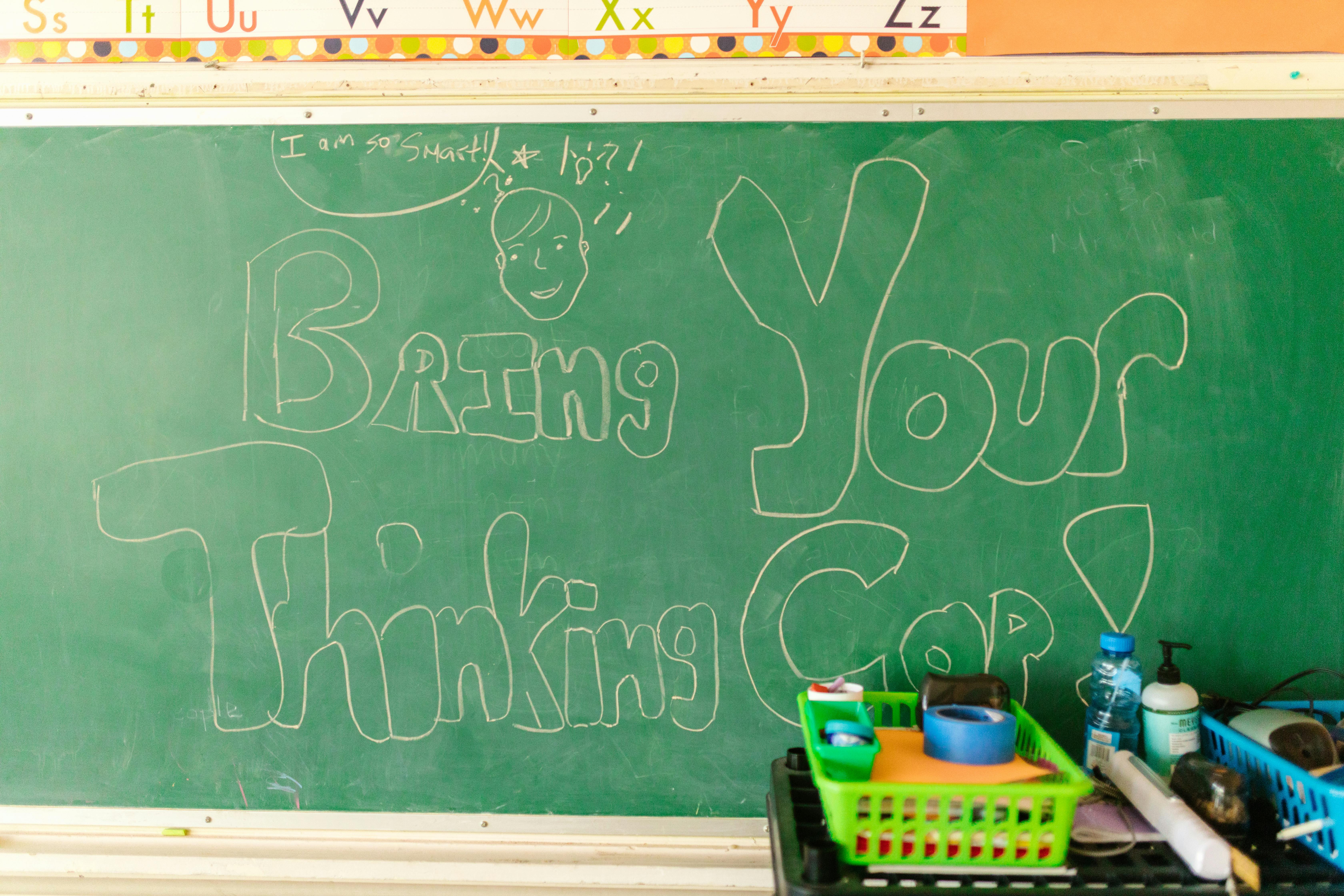 Classroom scene with chalkboard message "Bring Your Thinking Cap" and supplies.