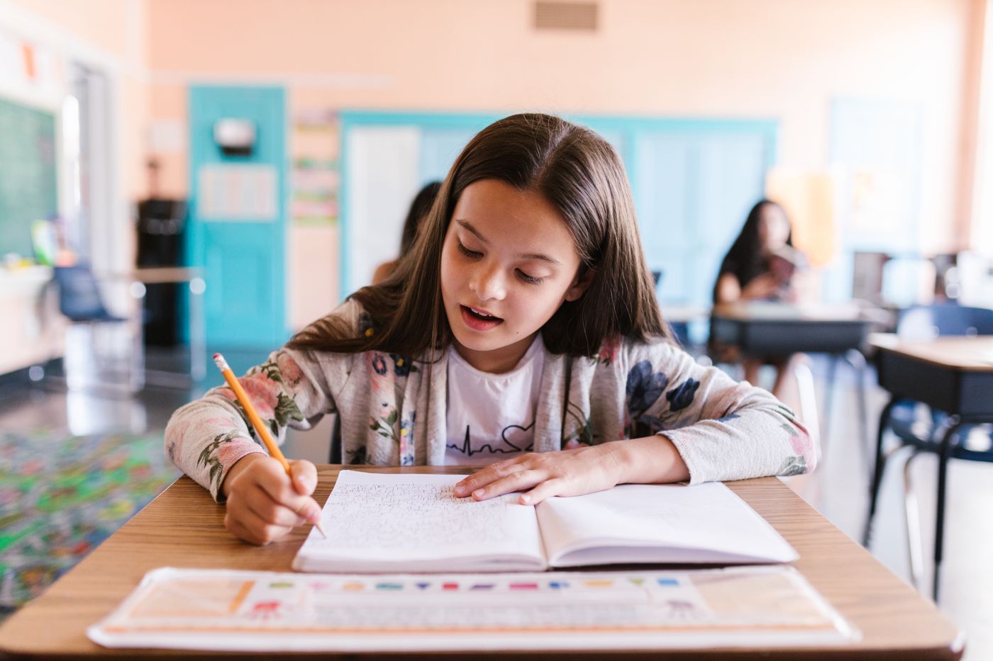 Alumna resolviendo ejercicios en su cuaderno durante una clase de grupo reducido en la academia Aristos