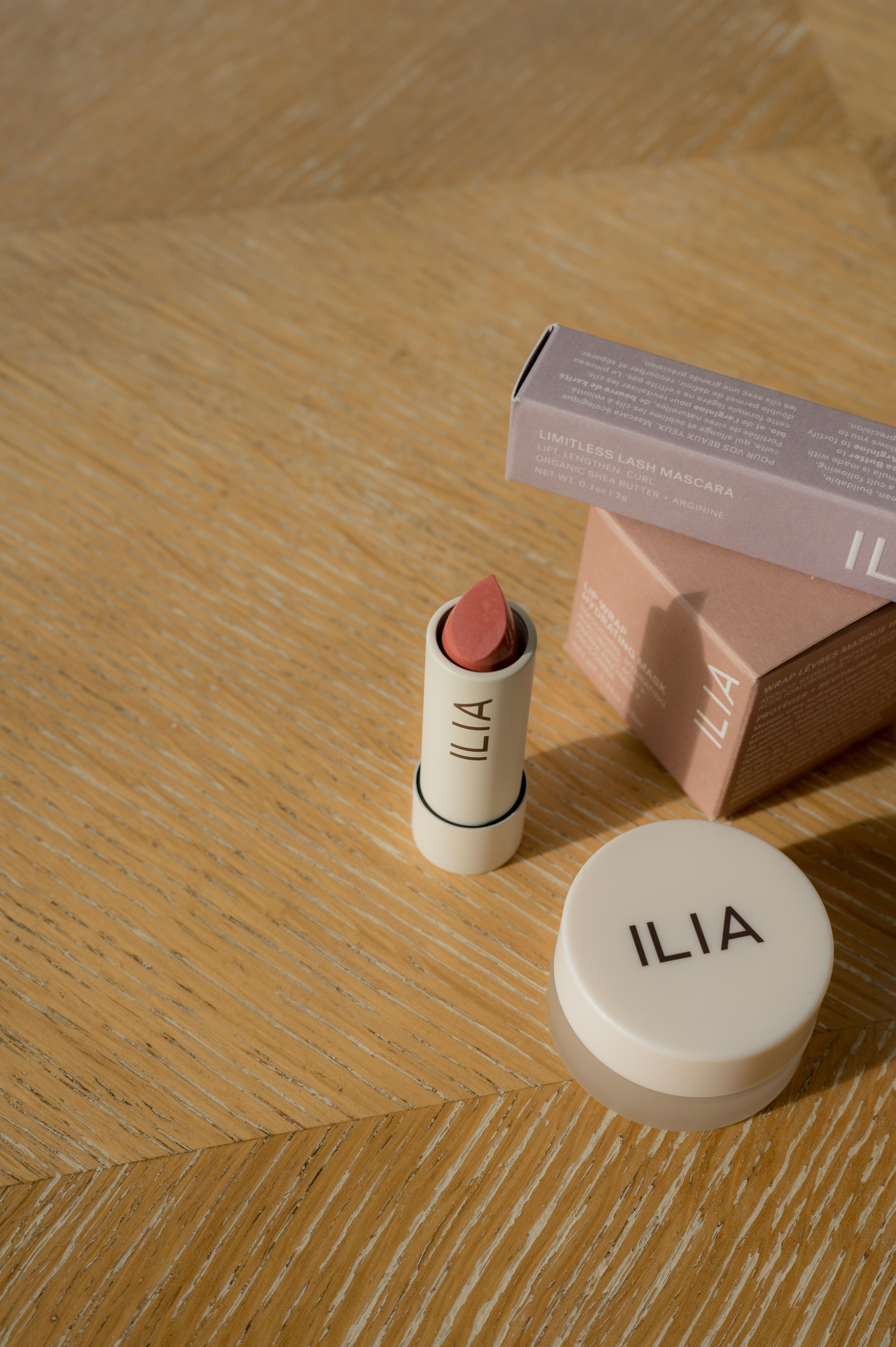 A vertical shot showcasing ILIA beauty products on a textured wooden surface.
