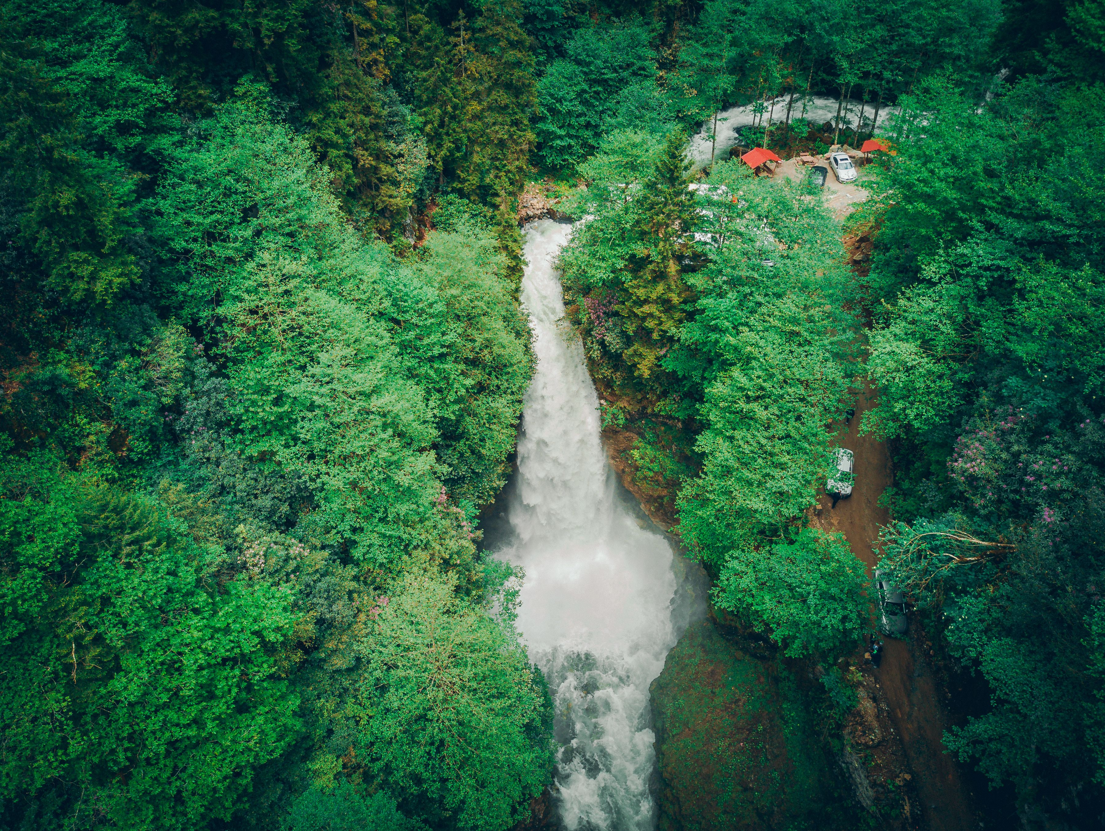 Drone shot capturing a waterfall cascading through dense green forest, offering a stunning natural view.