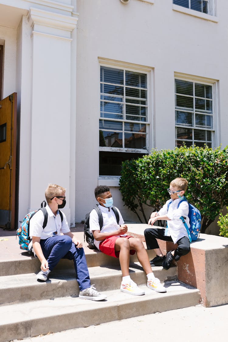 Students Wearing Face Masks Sitting On Concrete Steps 