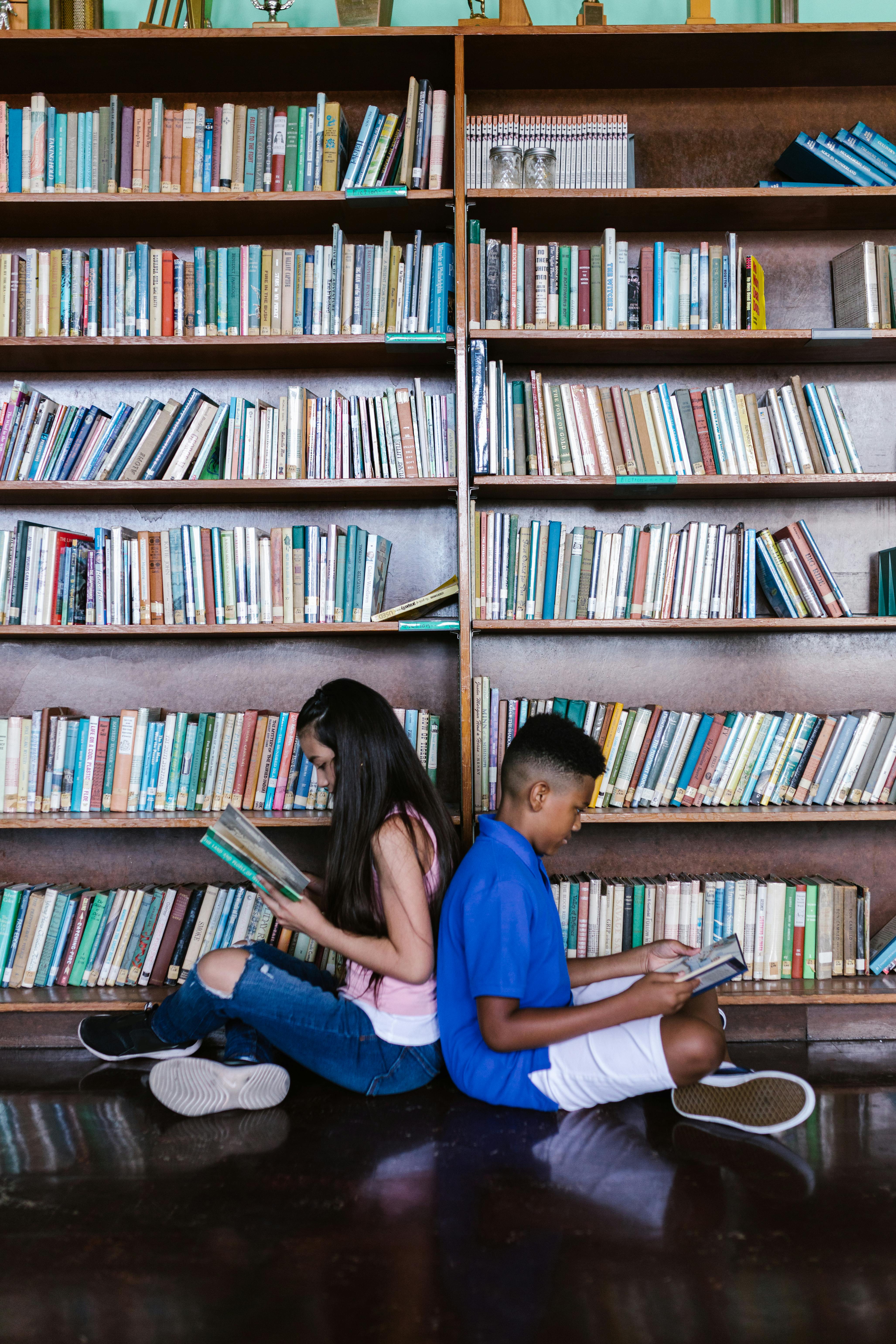 a boy and girl sitting back to back while reading books