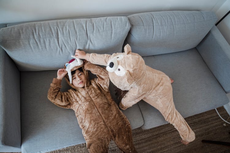 Cute Children In Funny Pajamas Lying On Sofa