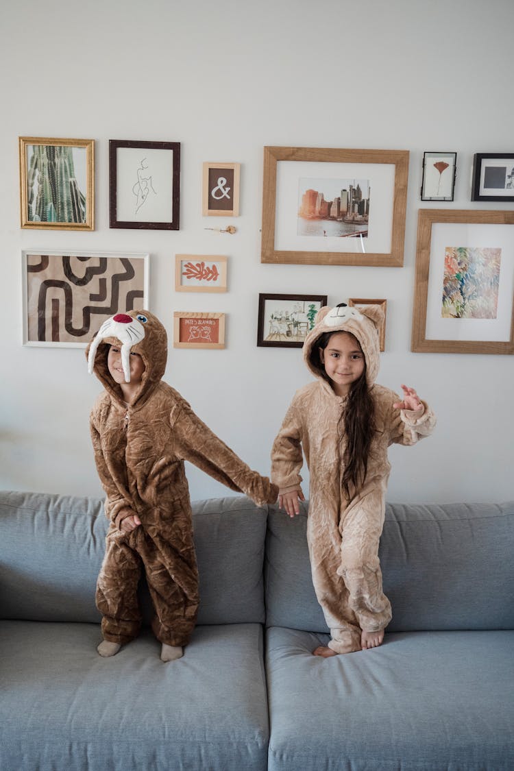 Kids In Onesies Standing On A Couch 