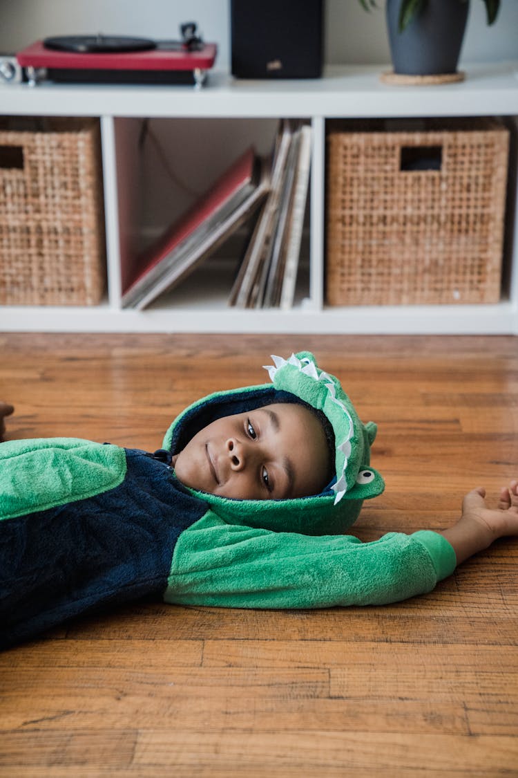 Boy In Animal Costume Lying On Wooden Floor