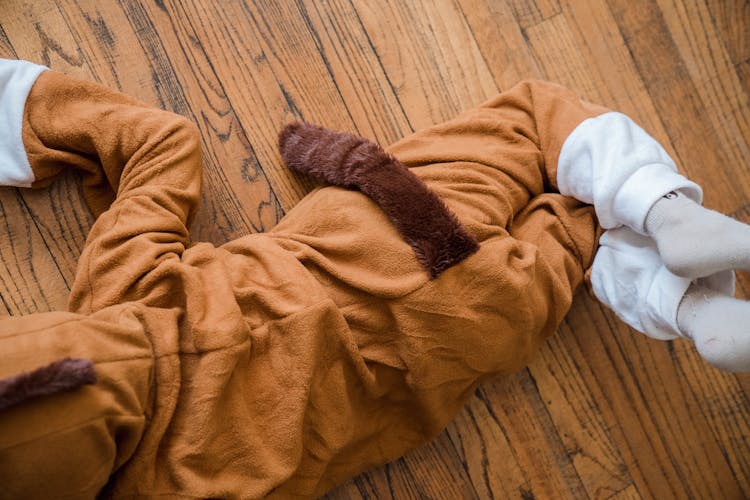 Boy In Tiger Costume Lying On Wooden Floor