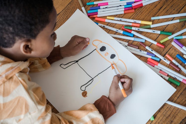 A Boy Drawing On A White Paper 