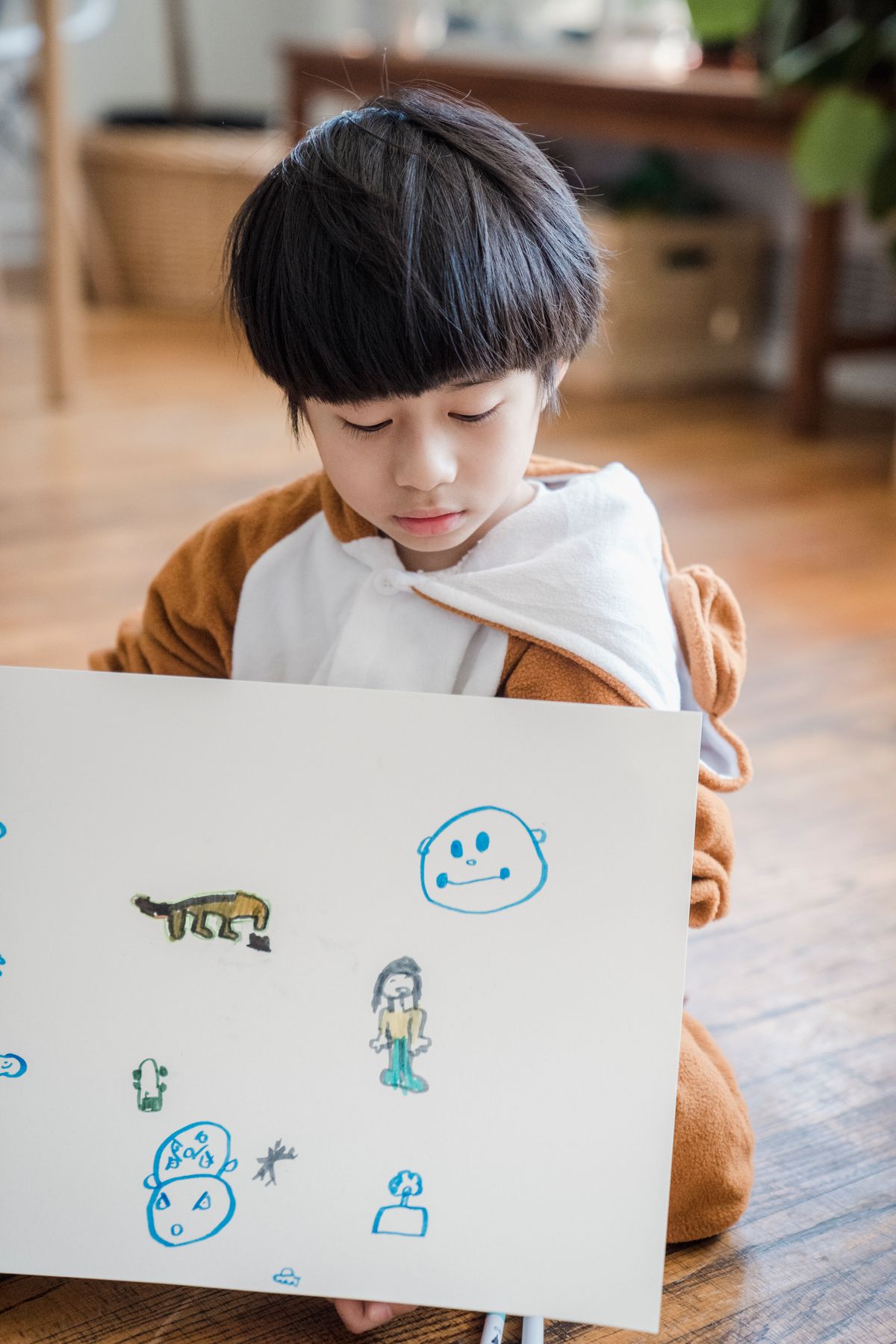 Child displaying hand-drawn animal sketches including a honey bee