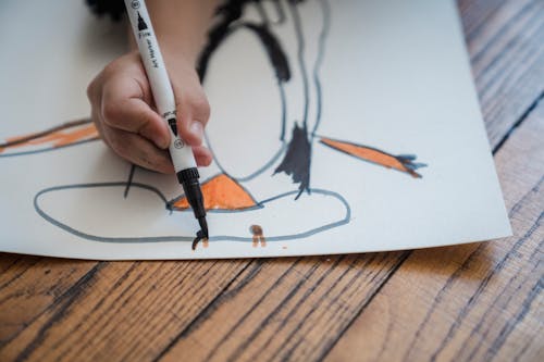 Close-Up Photo of a Child Holding Black Marker