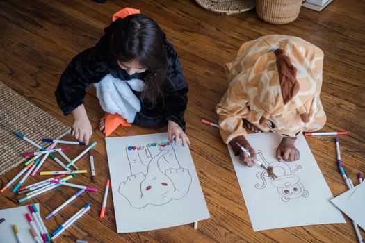 Children in animal costumes drawing on paper with colorful markers indoors.