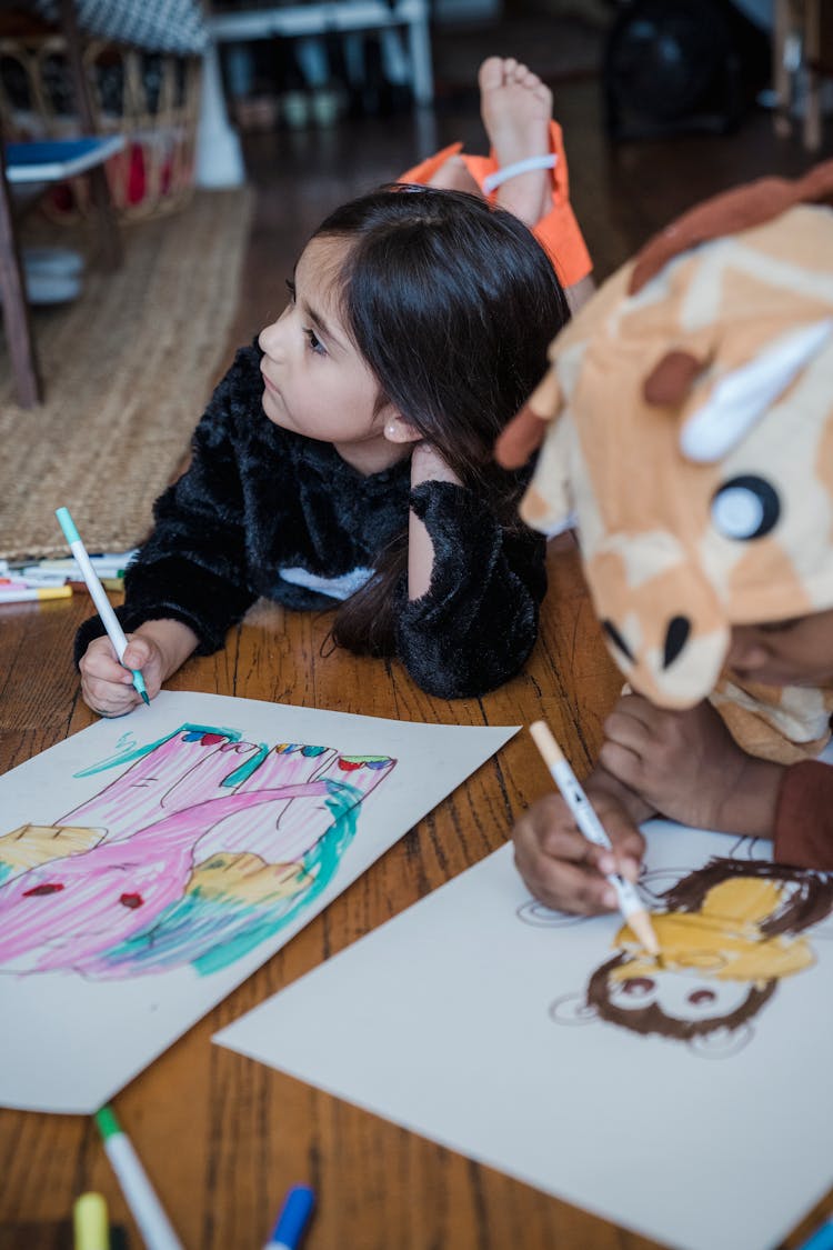 Girl Lying On The Floor Beside Boy And Drawing Pink Elephant