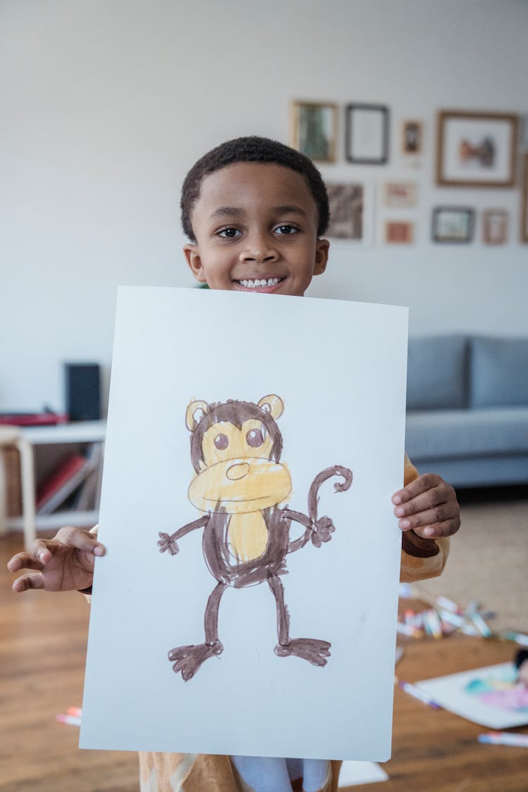 Smiling Boy Holding Drawing Of A Monkey