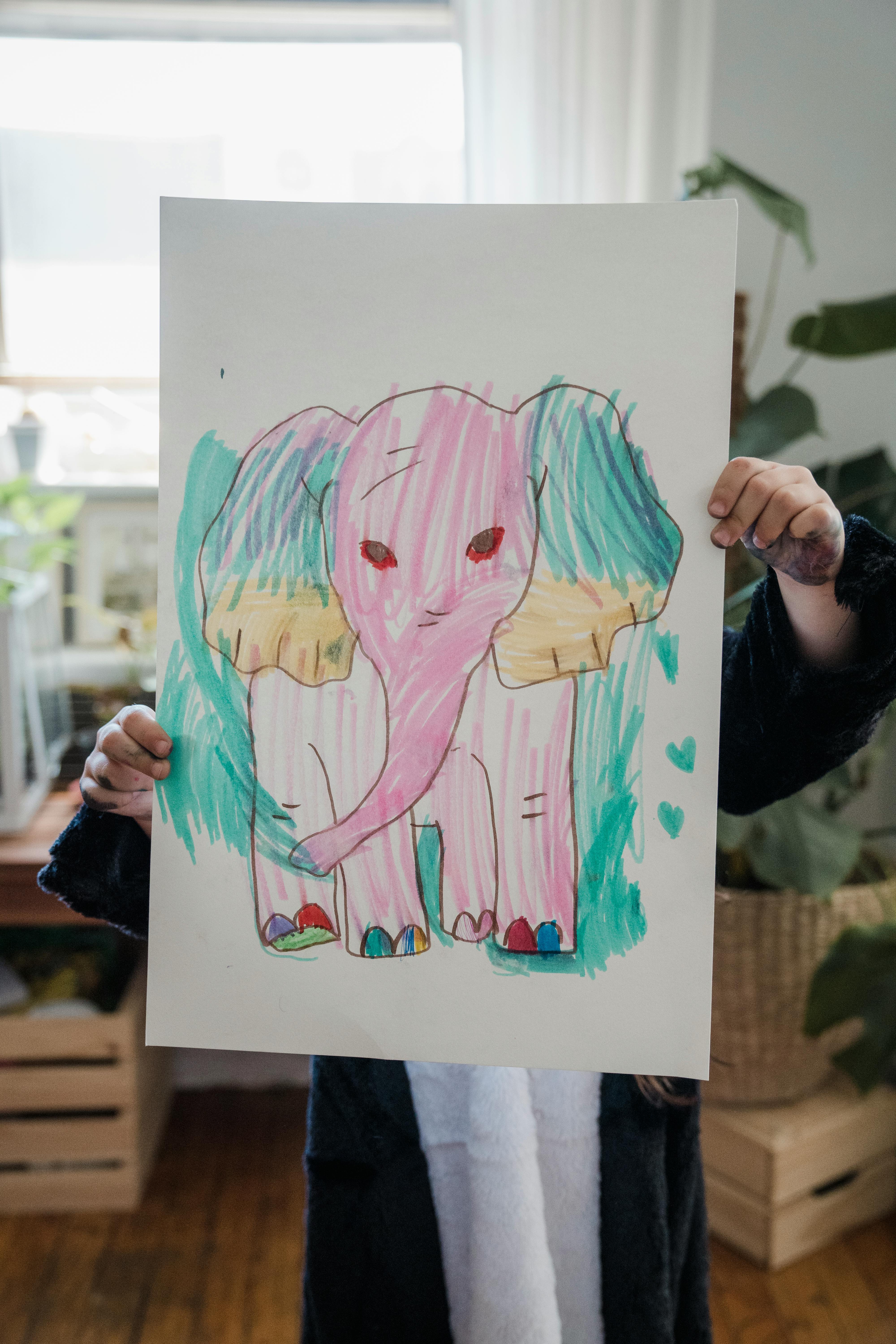 kid holding drawing of pink elephant