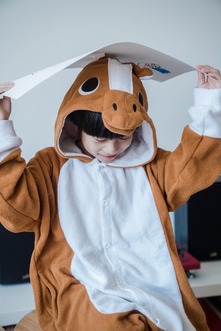 Boy In Animal Costume Holding Paper Above Head