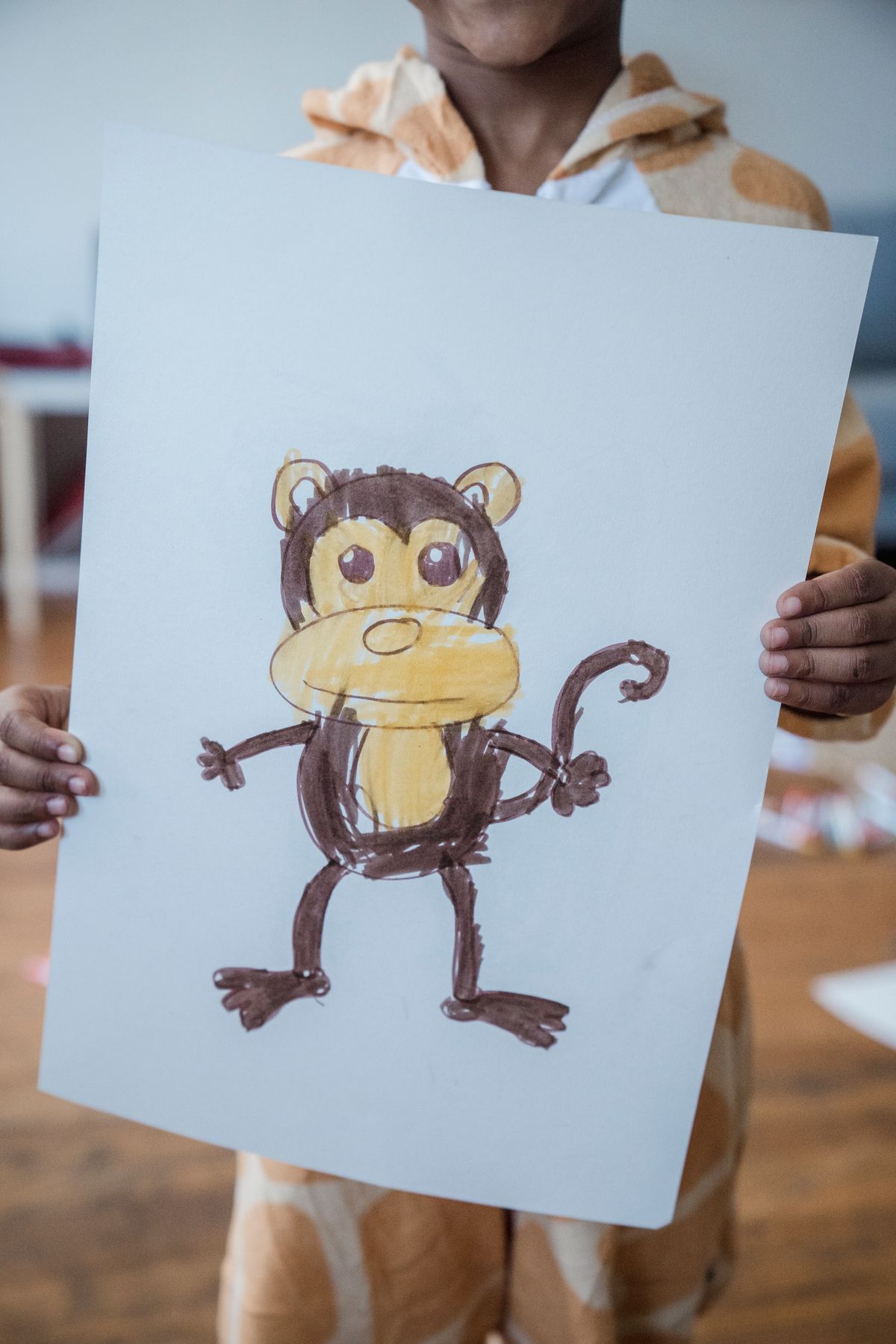 Child proudly holding a hand-drawn picture of a cartoon monkey